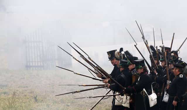 Performers wearing 19th century Allied forces military uniforms prepare to attack French forces during a reenactment of the Battle of the Nations, in a field in the village of Markkleeberg near Leipzig October 20, 2013. The east German city of Leipzig commemorated the 200th anniversary of the largest battle of the Napoleonic Wars on Sunday by reenacting the Battle of the Nations, with 6,000 military-historic association enthusiasts from all over Europe. The decisive encounter in which tens of thousands of soldiers were killed, took place from October 17-19, 1813, just outside of Leipzig. At the height of the hostilities Napoleon fielded more than 200,000 men against an Allied force of some 360,000 soldiers which included troops from Russia, Austria, Prussia and Sweden. (Photo by Fabrizio Bensch/Reuters)