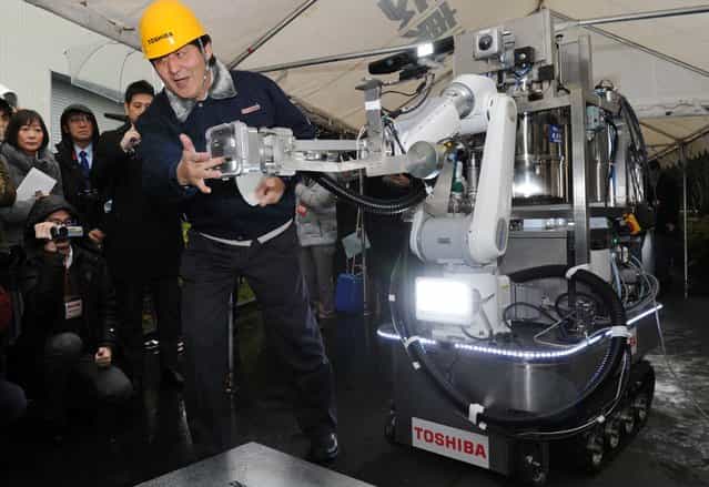 An engineer of Toshiba displays a decontamination robot, for work inside a nuclear plant, during a demonstration at Toshiba's technical center in Yokohama, suburban Tokyo on February 15, 2013. The crawler robot blasts dry ice particles against contaminated floors or walls and will be used for the decontamination in TEPCO's stricken Fukushima nuclear power plant. (Photo by Yoshikazu Tsuno/AFP Photo)