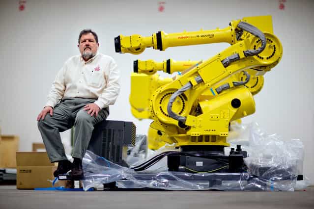 Rosser Pryor, Co-owner and President of Factory Automation Systems, sits next to a new high-performance industrial robot at the company's Atlanta facility, on January 15, 2013. Pryor, who cut 40 of 100 workers since the recession, says while the company is making more money now and could hire ten people, it is holding back in favor of investing in automation and software. (Photo by David Goldman/AP Photo)