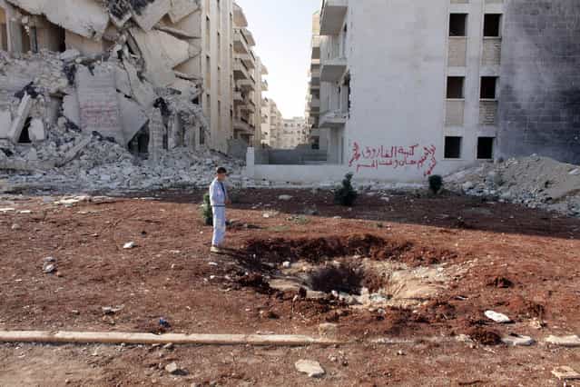Essay Finalist – William Wintercross. A boy stares into a bomb crater amidst damage to his neighbourhood in Aleppo. (Photo by William Wintercross/The Daily Telegraph)