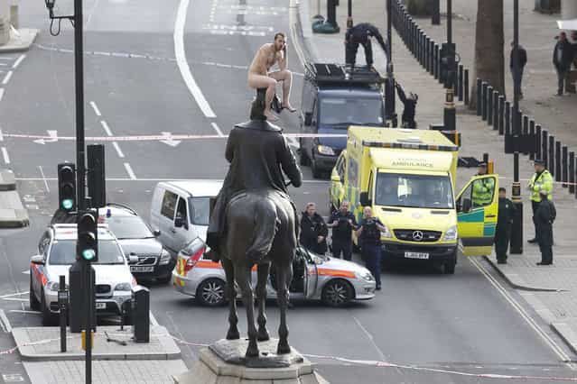 News Finalist – Justin Tallis. An unidentified man sits naked on top of the statue of Prince George, Duke of Cambridge outside the Ministry of Defence building in Whitehall in central London on November 23, 2012. The man, who brought Whitehall to a standstill for almost two hours, stood naked on the statue and struck various poses before being eventually talked down. (Photo by Justin Tallis/AFP Photo)