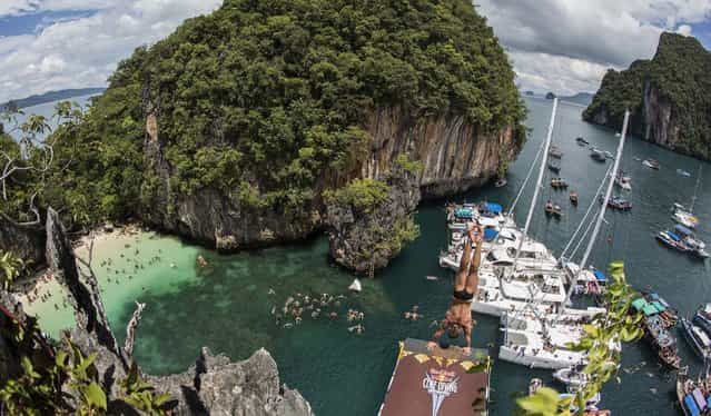In this handout image provided by Red Bull, Artem Silchenko of Russia prepares to launch an armstand dive from the 27 metre platform on Hong Island in the Andaman Sea during the last competition day of the eighth and final stop of the 2013 Red Bull Cliff Diving World Series on October 26, 2013 at Krabi, Thailand. (Photo by Romina Amato/Red Bull via Getty Images)