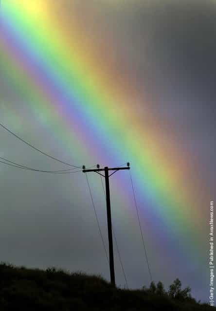 A rainbow appears in a stormy sky over a power line near San Fernando