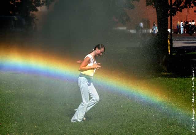 A girl runs through a water sprinkler escaping the heat in Alexandrovski Garden July 15, 2002 in Moscow, Russia