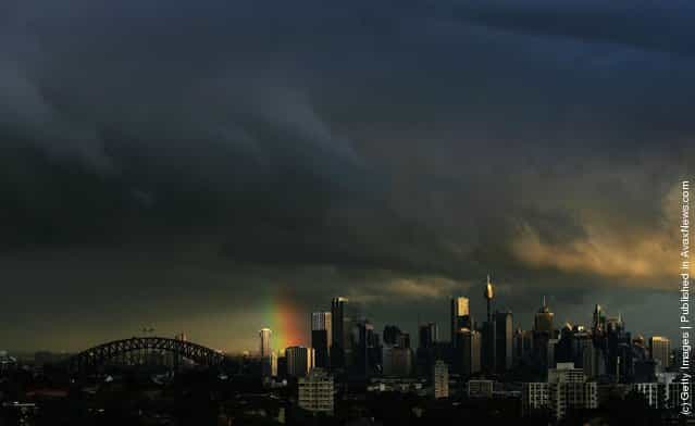 A rainbow appears over the Sydney Harbour Bridge (L) as storm clouds gather over the city skyline at sunset July 20, 2006 in Sydney, Australia