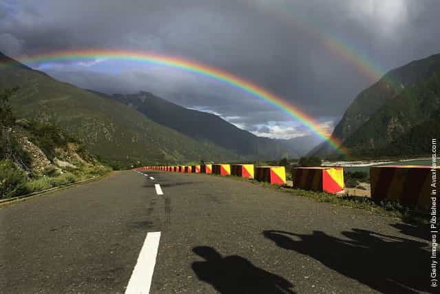 Tourists take pictures of a rainbow at a highway in Nyingchi County of Lhasa
