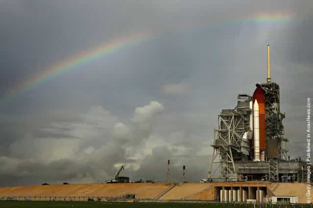 Rainy skies produce a rainbow over the space shuttle Atlantis as it stands on launch pad 39A one day before its scheduled launch at Kennedy Space Center