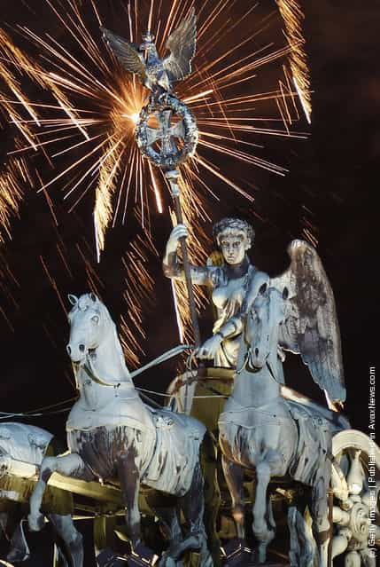 Fireworks explode over the Quadriga statue atop the Brandenburg Gate on New Years Eve on January 1, 2012 in Berlin
