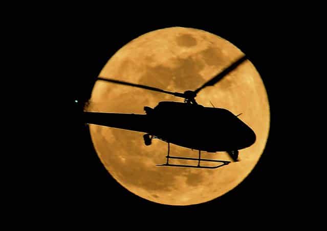 LAPD chopper flies in a foregraund of the Super Moon in Los Angeles, California on May 05, 2012
