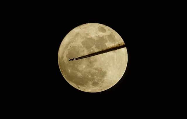 A plane flies past the moon as seen from Somerset in southern England