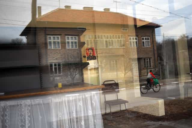 A reflection of a building in the windows of an empty shop bearing the picture of Soviet leader Joseph Stalin