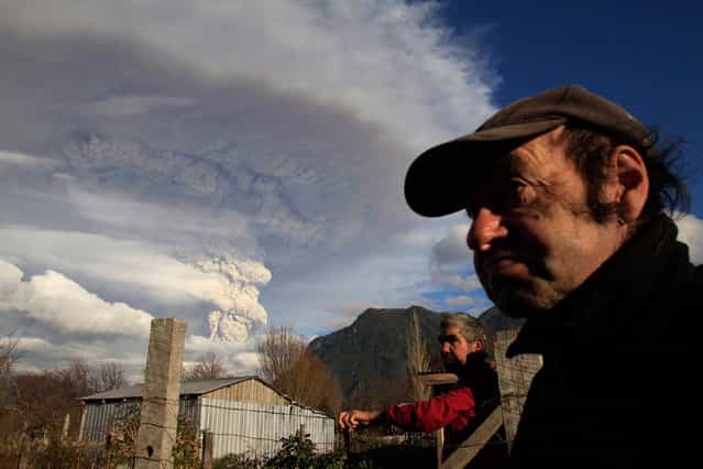 Locals stay in front of their home as ash and steam rise from the Puyehue-Cordon Caulle volcanic chain near Osorno city in south-central Chile June 5, 2011