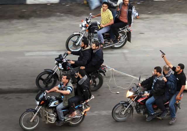 Palestinian gunmen ride motorcycles as they drag the body of a man, who was suspected of working for Israel, in Gaza City November 20, 2012. Palestinian gunmen shot dead six alleged collaborators in the Gaza Strip who [were caught red-handed], according to a security source quoted by the Hamas Aqsa radio on Tuesday. (Photo by Suhaib Salem/Reuters)