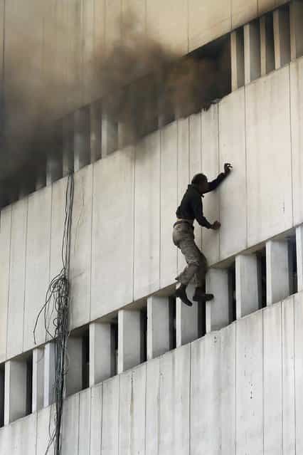 A man falls from a high floor of a burning building in central Lahore May 9, 2013. Fire erupted on the seventh floor of the LDA plaza in Lahore and quickly spread to higher floors leaving many people trapped inside the building. At least three people fell from the high floors trying to avoid the fire that engulfed the building, local media reports. (Photo by Damir Sagolj/Reuters)