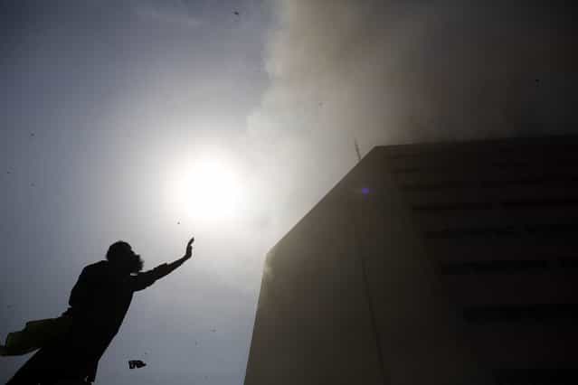 A man gestures toward a rescue helicopter as it approaches a burning building in central Lahore May 9, 2013. Fire erupted on the seventh floor of the LDA plaza in Lahore and quickly spread to higher floors leaving many people trapped inside the building. At least three people fell from the high floors trying to avoid the fire that engulfed the building, local media reports. (Photo by Damir Sagolj/Reuters)