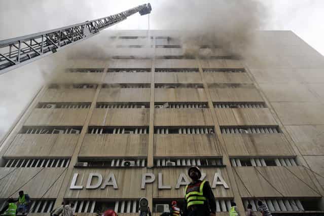 Rescue workers try to save people trapped inside a burning building in central Lahore May 9, 2013. Fire erupted on the seventh floor of the LDA Plaza in Lahore and quickly spread to higher floors leaving many people trapped inside the building. (Photo by Damir Sagolj/Reuters)