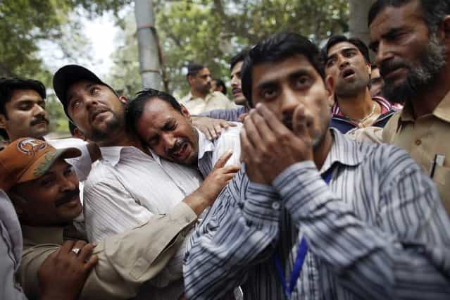 A man (C) who just left a burning building is comforted by bystanders, in central Lahore May 9, 2013. (Photo by Damir Sagolj/Reuters)
