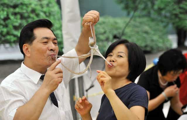 A South Korean man and a woman eat a live octopus during an event to promote a local food festival in Seoul on September 12, 2013. (Photo by Jung Yeon-Je/AFP Photo)