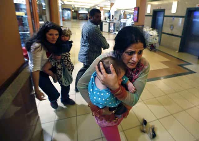 Women carrying children run for safety in the mall. (Photo by Goran Tomasevic/Reuters)