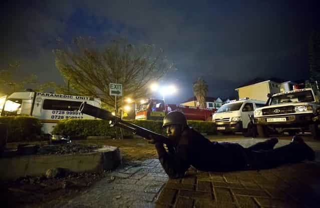 A police officer takes cover outside the Westgate Mall as the search for the gunmen continues. (Photo by Ben Curtis/Associated Press)