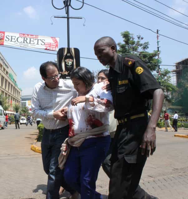 A security officer helps a wounded woman outside the Westgate Mall in Nairobi, Kenya on Saturday, September 21 2013, after gunmen threw grenades and opened fire during an attack that left multiple dead bodies and dozens wounded. (Photo by Jason Straziuso/AP Photo)