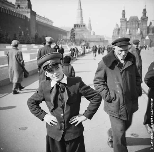 1954: A Russian boy in school uniform stands in Red Square, Moscow. To the left is the wall of the Kremlin and in the background, Lenin's mausoleum