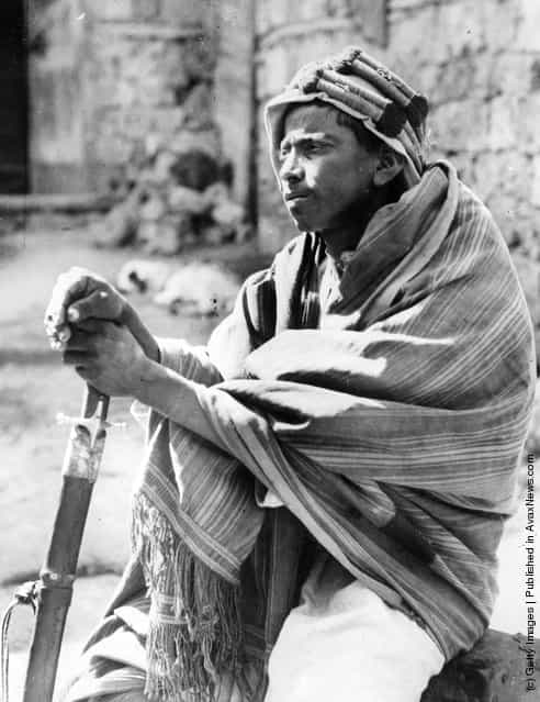 1930: A young bedouin 'spy' in Jiddah (Jedda) leans on his sword as he keeps watch