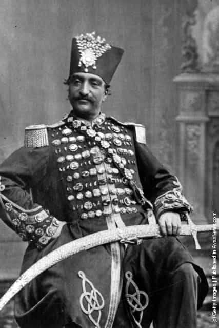 circa 1880: Nasiruddin, Shah of Persia (Iran) in regal attire, with his scimitar