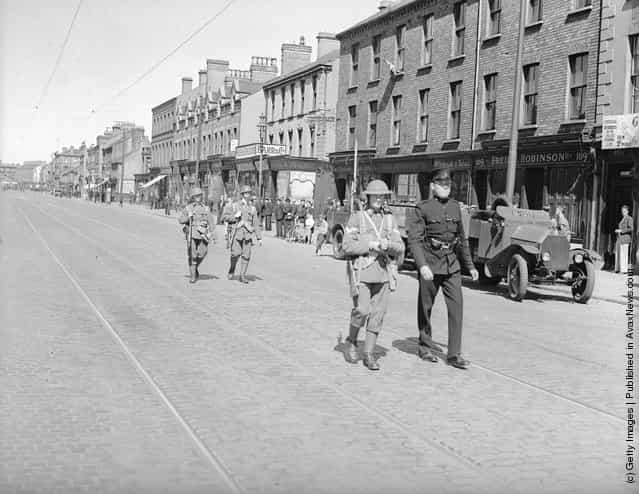 1935: Police and military patrolling York street, Belfast, clear of traffic after recent rioting. An armoured car ia parked at the kerb