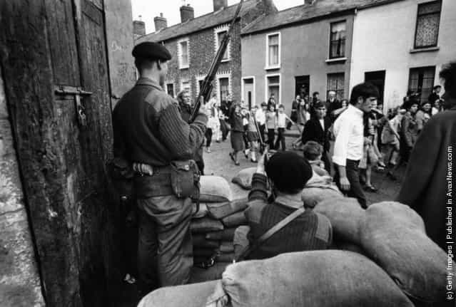 1970: Marchers on a civil rights demonstration in Belfast pass by an armed British Army sentry point