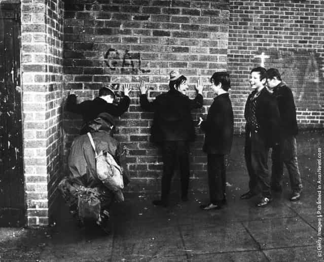 1971: Schoolboys giggling while a soldier searches them in a street in the Ardoyne area of Belfast