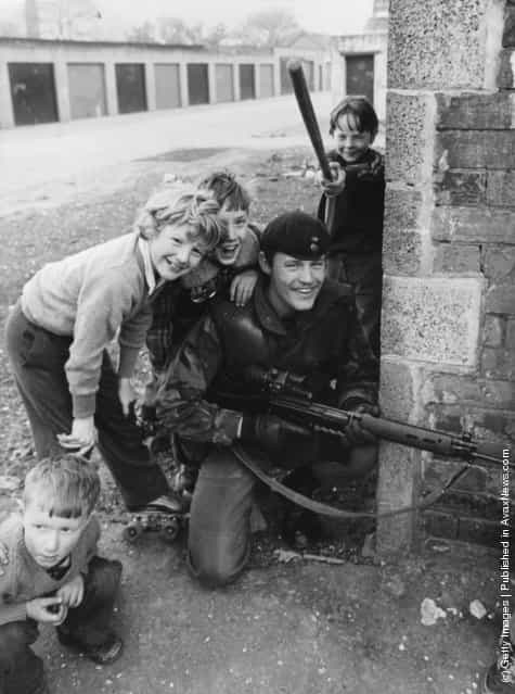 1981: Schoolboys in a Catholic area of Belfast at play on the streets near a British soldier on patrol