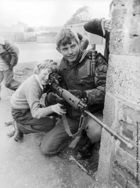 1981: A British soldier lets a young boy look through the sights of his rifle in Belfast