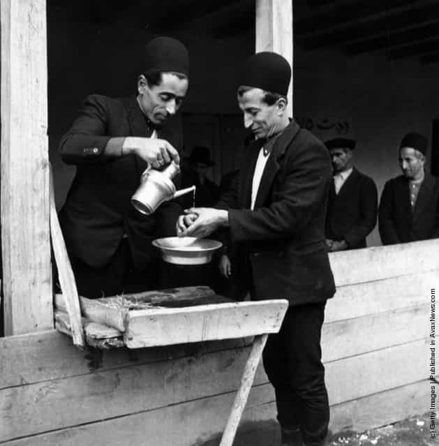 1950: Two men perform the customary handwashing ceremony at a traditional Muslim wedding in the Mazanderan province of Iran