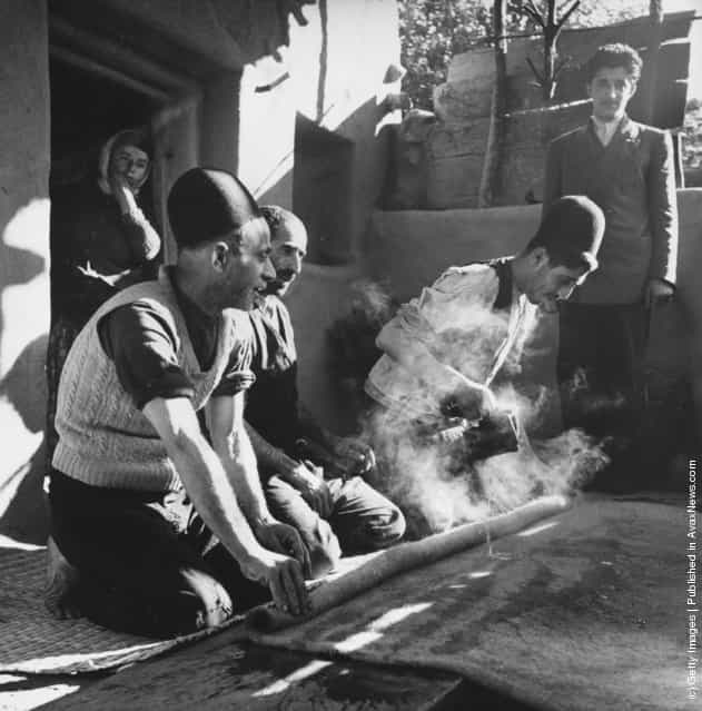 1950: Iranian peasants making rugs by kneading pieces of wool together after steaming them under pressure
