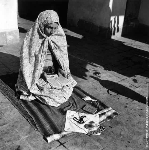 1955: A woman reading from the Koran during her prayers which she makes five times a day
