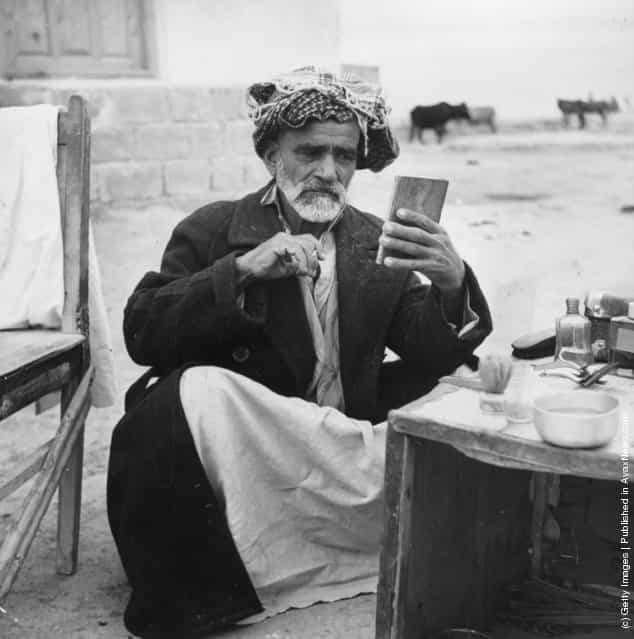 1955: A Muslim man trims his beard at a self service barber shop at Aga Uhari, Iran