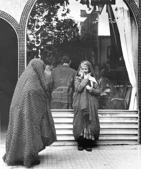 1955: Iranian women wait outside whilst the men meet in a teashop in Mashad, Iran