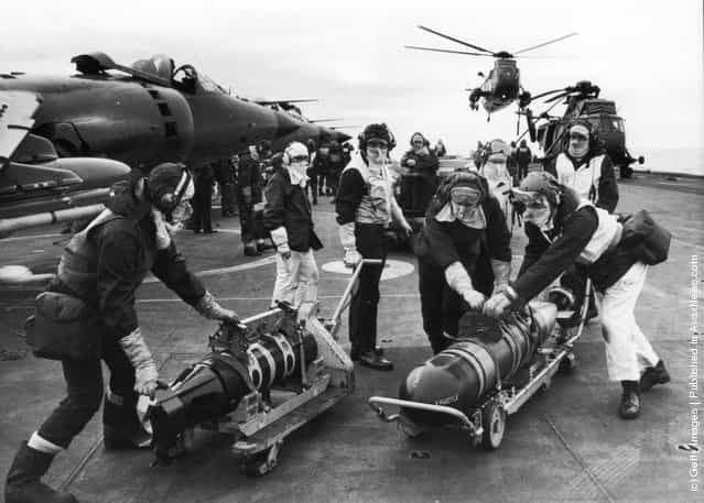 Armourers moving torpedoes on the flight deck of HMS Hermes during the Falklands conflict, May 1982. The torpedos are to re-arm Sea King helicopters to counter the threat from Argentinian submarines