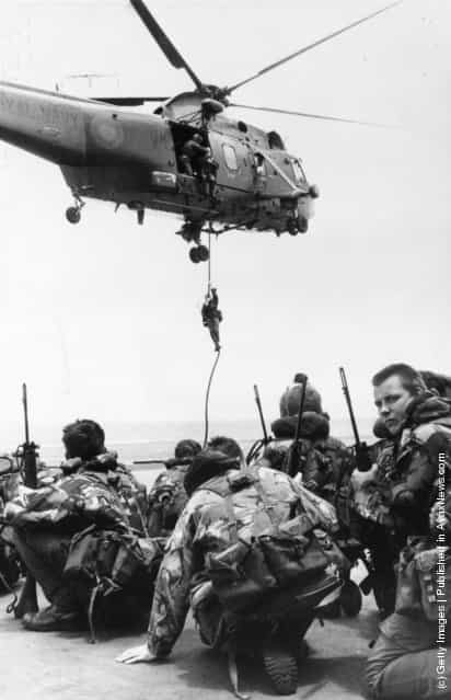 Waiting to be lifted by a Westland Sea King helicopter, Royal Marines from 40 Commando crouch on the flight deck of HMS Hermes, which heads the naval task force bound for the Falkland Islands