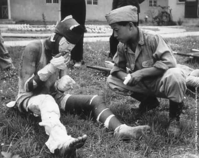 A severely wounded Korean soldier smoking a cigarette in the grounds of an advance casualty cleaning unit, 1950