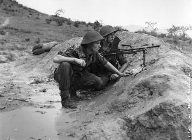 Two soldiers, guns at the ready, keep watch for enemy advance in Korea, 1950