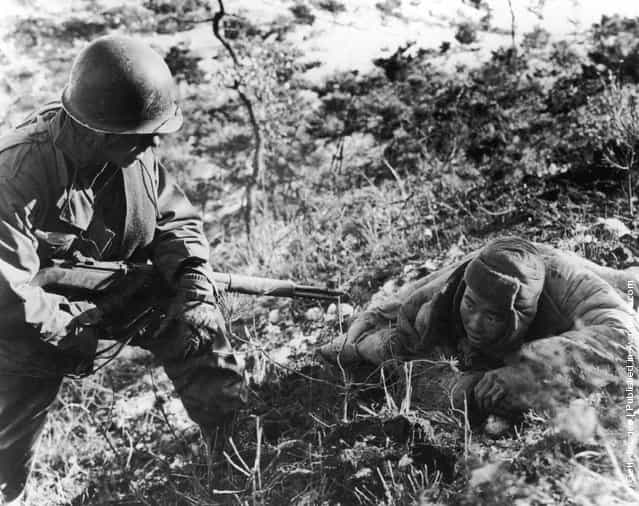An American soldier taking a communist prisoner during the Korean war, 1952