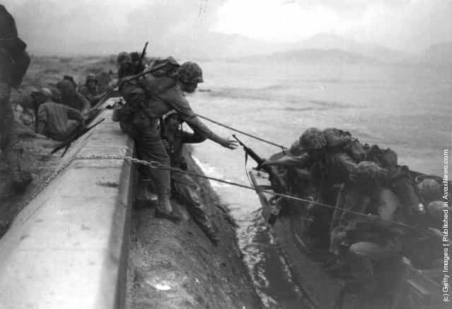 US Marines land from assault craft and climb over the sea defences at Inchon in South Korea during the Korean War, after heavy bombardment of coastal defences by warships