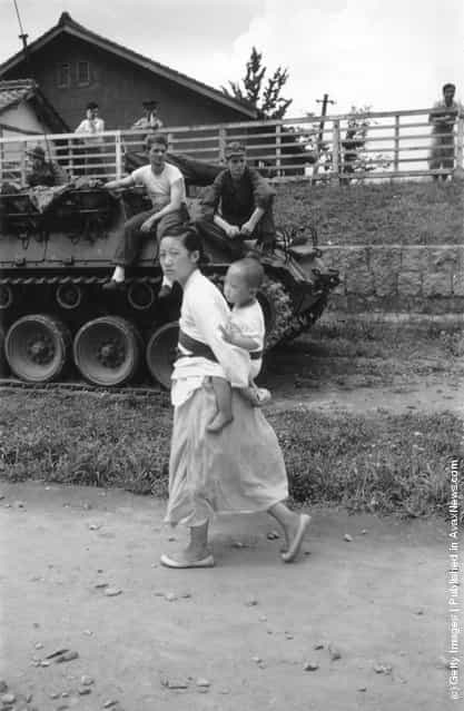 1950: A Korean refugee and her child are watched by an American tank crew during the retreat south of US and Korean troops after the North Koreans crossed the 38th Parallel