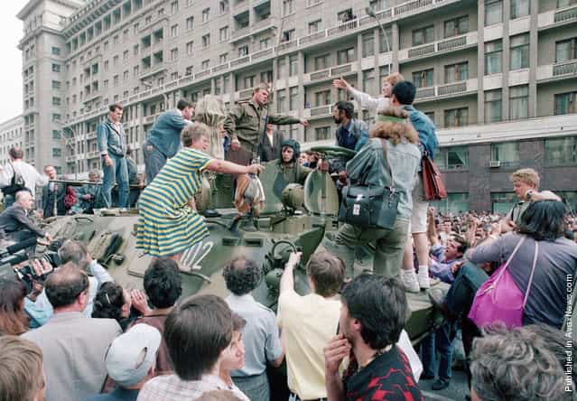 A crowd gathers around a personnel carrier as some people climb aboard the vehicle and try to block its advance near Red Square in downtown Moscow, on August 19, 1991. Military vehicles were on the streets of Moscow following the announcement that Soviet President Mikhail Gorbachev was replaced by Gennady I. Yanayev in a coup attempt by hard-line Communists