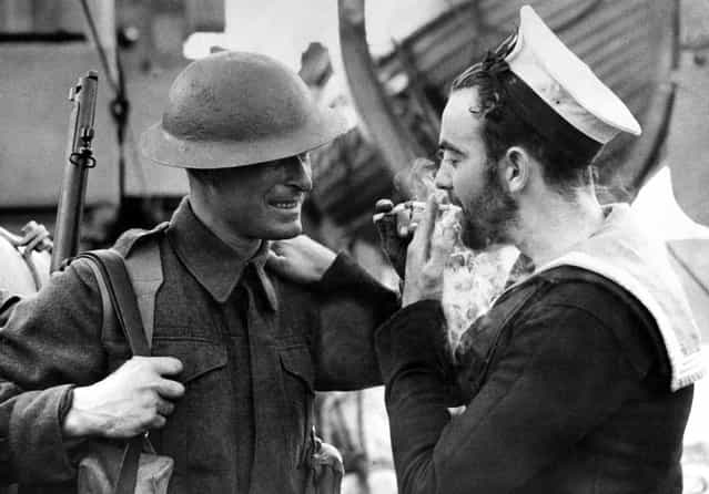 Two examples of Britain's war forces, a soldier in battle dress and a bearded Canadian sailor share a light at an English port, on January 14, 1941