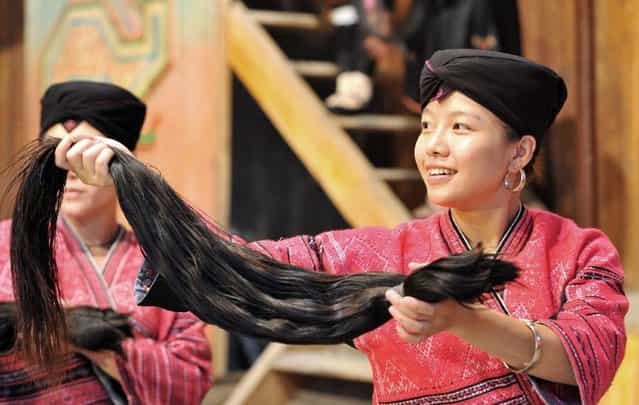A woman shows the hair cut off from a 18-year-old girl to tourists at the Huangluo Village of the Yao ethnic group in Guilin, south China's Guangxi Zhuang Autonomous Region, July 15, 2012. The Huangluo Village of the Yao ethnic group locates at the Longji Terraces in Heping Town of Longsheng County in Guilin. Women here have the tradition of keeping long hair. They believe that long hair brings good luck and fortune. The average length of hair of 180 women in the village is 1.7 meters. (Photo by Lu Boan/Xinhua)