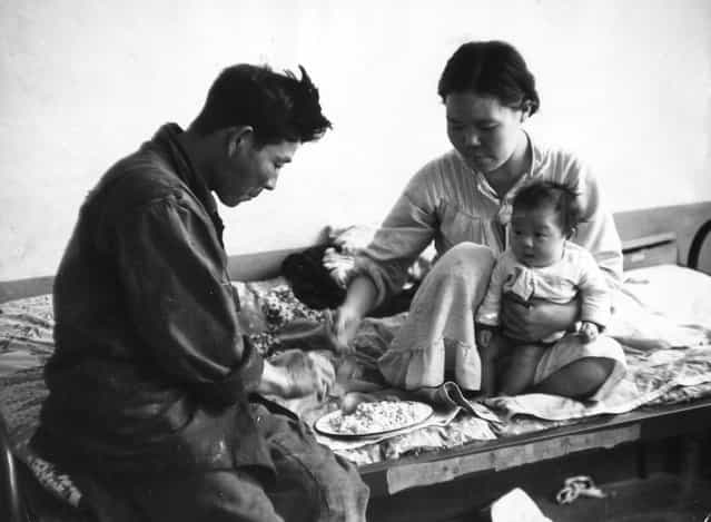 A Korean family share a bowl of rice on a bed in a refugee camp, still homeless nearly five years after the Korean war ended. 23rd July 1955. (Photo by John Chillingworth)