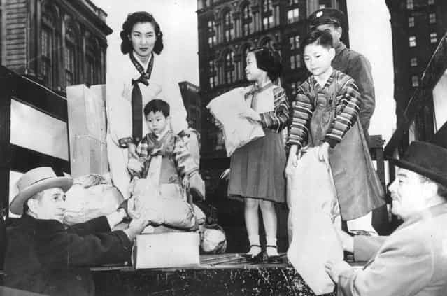 Grover Whalen, right, chairman of the Korea Clothes Drive, donating a bag of clothes to be sent to Korean war victims, 22nd November 1951. (Photo by Keystone)